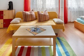 A room with a yellow sofa, striped pillows, a white coffee machine, and a colorful table runner. - Studio Apartment 'Ferienwohnung Zur Schauinslandbahn' with Mountain View, Private Terrace and Wi-Fi (Horben)
