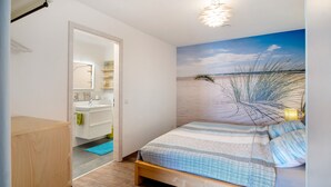 Ein Schlafzimmer mit Bett, ein Badezimmer mit Waschbecken und einer Tür zu einem anderen Raum.