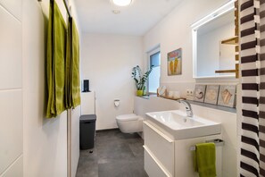 Een badkamer met toilet, wastafel en groene handdoeken.