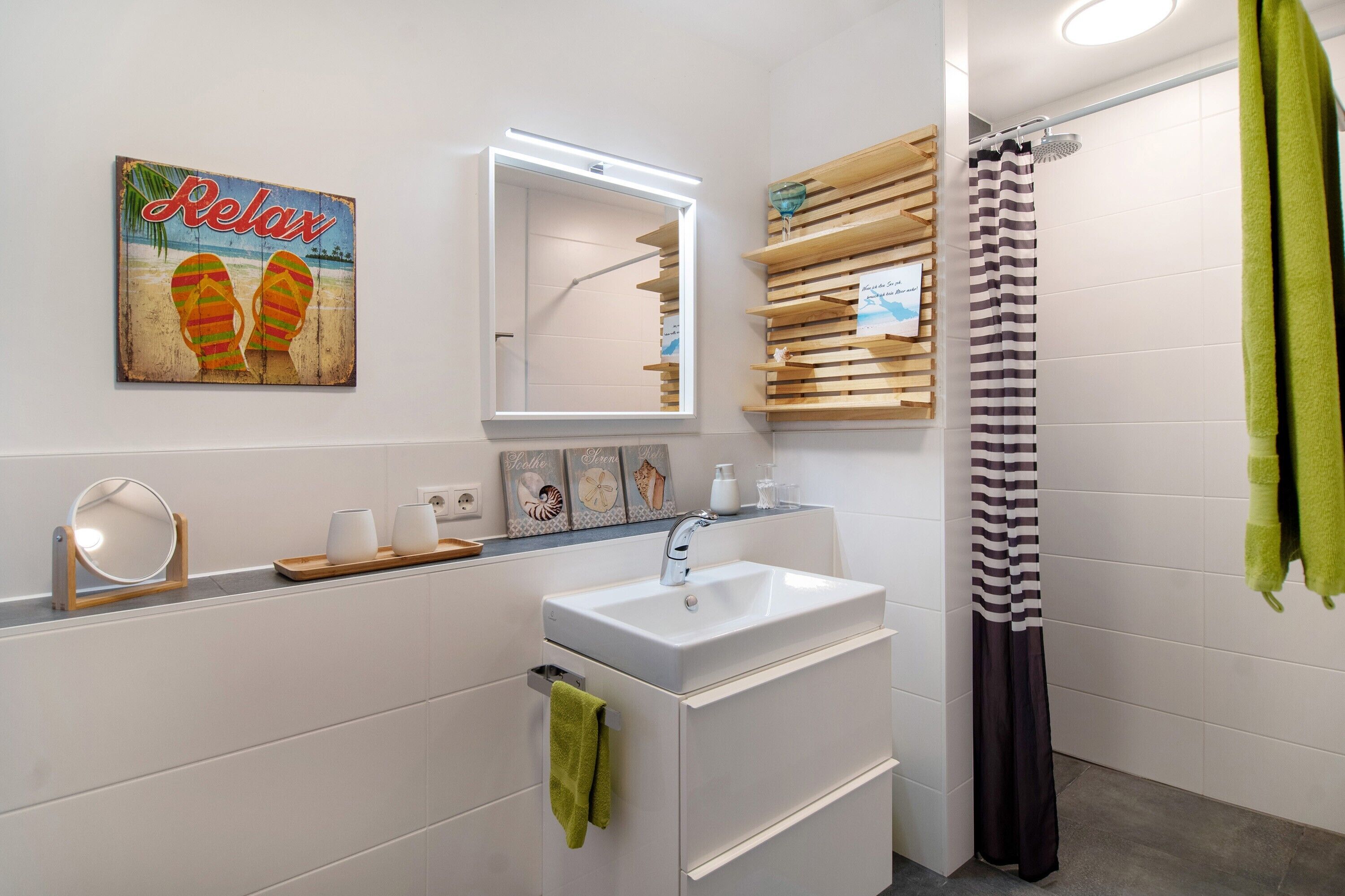 A bathroom with a white sink, mirror, and wooden shelf with decorative items.