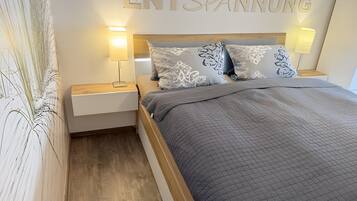 Une chambre d’hôtel avec un lit, deux lampes de chevet, une table de nuit et un mur sur lequel est inscrit en grandes lettres le mot « ENTSPANNUNG ».