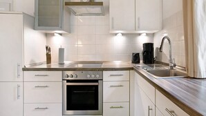 A modern kitchen with white cabinetry, a stainless steel oven, a sink, and a coffee maker. - Apartment 'Green Oasis Ferienwohnung' with Shared Terrace, Shared Garden and Wi-Fi (Treia)
