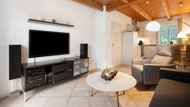 A modern living room with a flat-screen TV, dark entertainment unit, white coffee table, and comfortable seating. - Apartment 'Green Oasis Ferienwohnung' with Shared Terrace, Shared Garden and Wi-Fi (Treia)