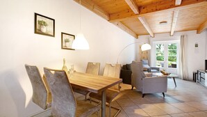 A dining area with a wooden table and chairs, a sofa, and a television. - Apartment 'Green Oasis Ferienwohnung' with Shared Terrace, Shared Garden and Wi-Fi (Treia)