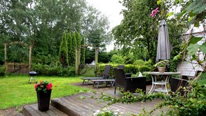 A wooden deck with outdoor furniture, a pergola, and a garden area. - Apartment 'Green Oasis Ferienwohnung' with Shared Terrace, Shared Garden and Wi-Fi (Treia)