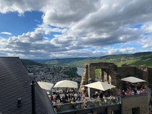 A rooftop terrace with stone ruins, outdoor seating, and a view of a town and hills. - The Red Holiday Home Terlinden – Charming Winemaker’s House in Lieser on the Moselle (Lieser)