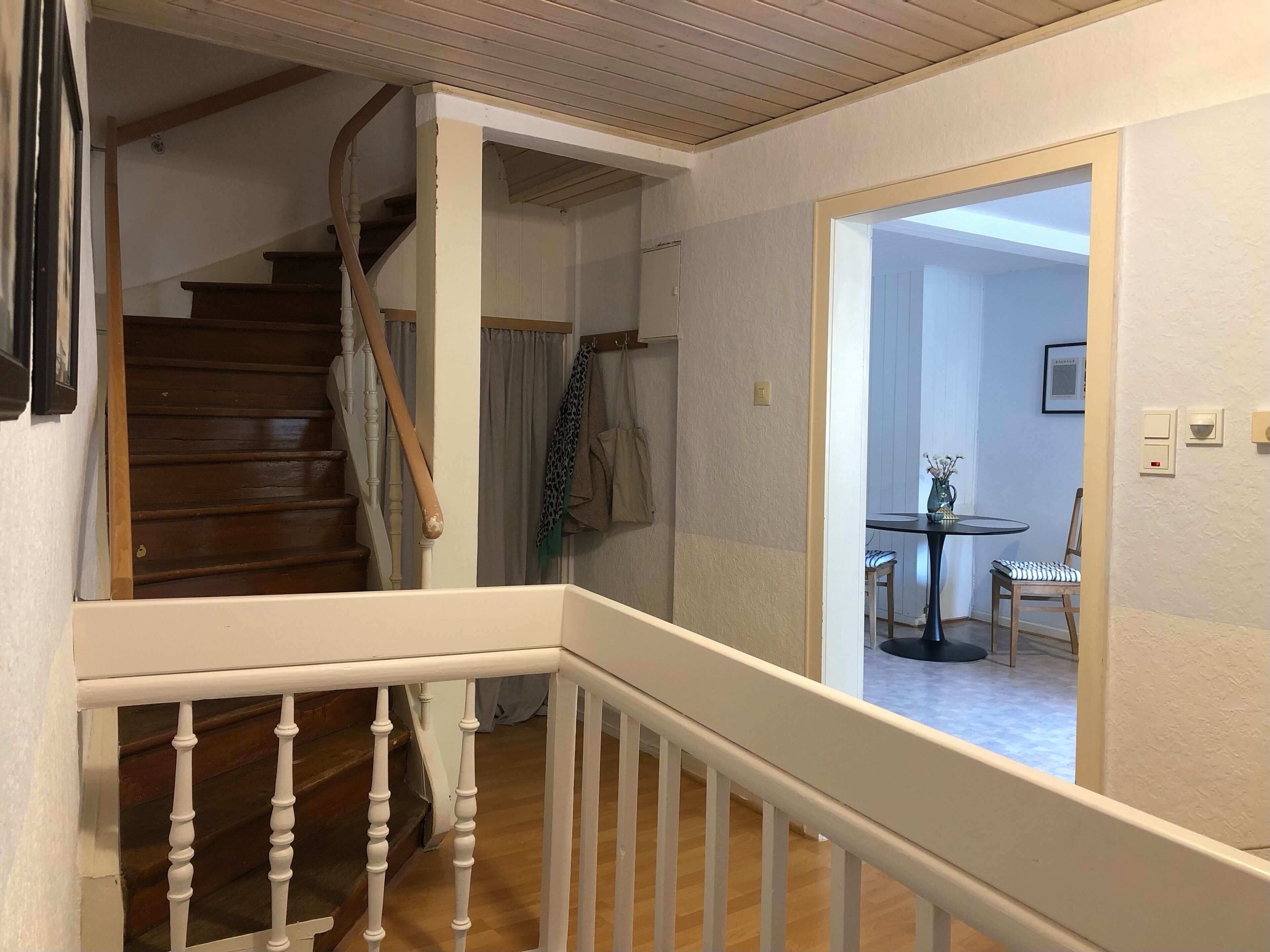 Una escalera con barandillas blancas que lleva a una habitación con una mesa y sillas para comer.