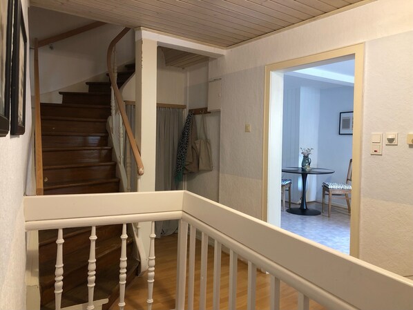 A staircase with white railings leading to a room with a dining table and chairs.