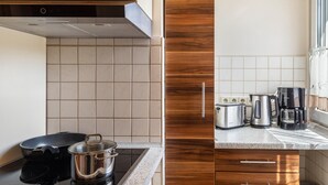Una cocina con estufa, olla, tostadora y cafetera.