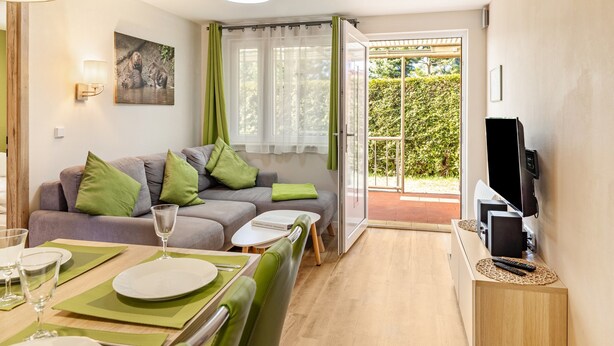 A modern living room with a sofa, dining table, and a TV. - Holiday Home 'Ferienhaus Biber' with Private Terrace, Private Garden and Wi-Fi (Stechow-Ferchesar)
