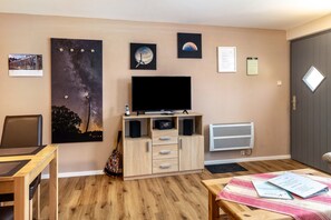 Une pièce dotée d’un téléviseur à écran plat, d’une armoire en bois et d’œuvres d’art murales.