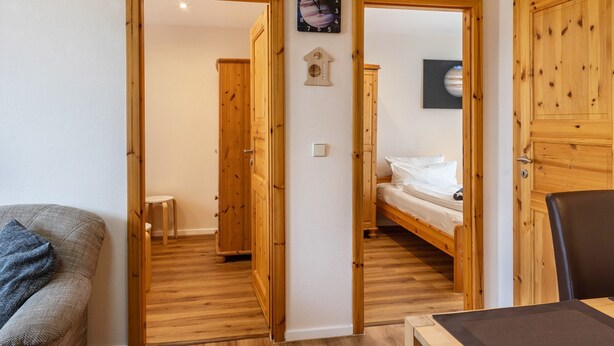 Una habitación con piso de madera, una cama, una mesita y un sofá.