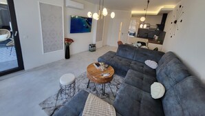 En moderne stue med en grå hjørnesofa, et træsofabord og et fjernsyn monteret på væggen.