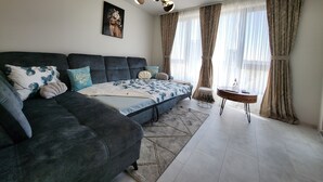 En moderne stue med en mørkegrå sofa, et mønstret pled og et lille sofabord med en vase.