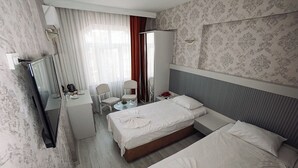 Una habitación de hotel con dos camas, un escritorio, una silla, un televisor y un armario.