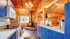 Ein Holzblockhaus-Innenraum mit Küche, Kamin und einem Schild, das Gäste willkommen heißt.