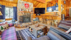 Ein gemütliches Blockhaus-Interieur mit Kamin, Fernseher und einer komfortablen Sitzecke.