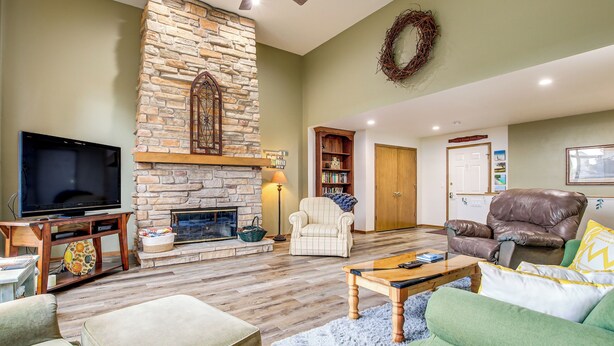 Una sala de estar con chimenea de piedra, televisor, estantería y sillón de cuero.
