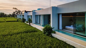 A modern hotel with a pool, large windows, and a grassy landscape. - GREEN FLOW Villas III Ubud (Ubud)