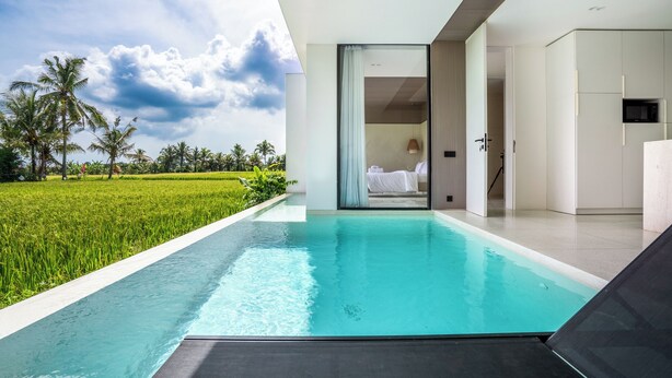 A modern hotel room with a private pool, a view of a lush green field, and a minimalist interior design. - GREEN FLOW Villas III Ubud (Ubud)