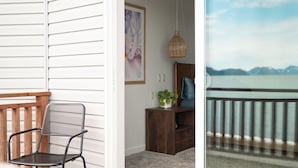 Une pièce avec une chaise en bois, une petite table sur laquelle se trouve une plante, et un tableau encadré accroché au mur.