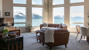 Un salon chaleureux avec une grande fenêtre donnant sur un paysage montagneux.