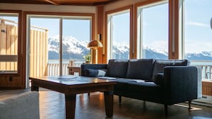 Une pièce avec un plafond en bois, de grandes fenêtres, un canapé et une table.