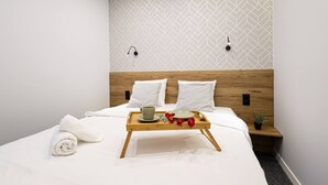 A neatly made bed with white linens, a tray with a cup and plate, and a small potted plant on a bedside table. - Estrella 8 Wypoczynek i Wygoda Toru Stare Miasto (Torun)
