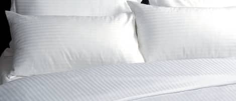 A neatly made bed with white linens and pillows.