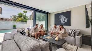 Un salon moderne avec vue sur la piscine, une grande fenêtre et une œuvre d’art encadrée accrochée au mur.