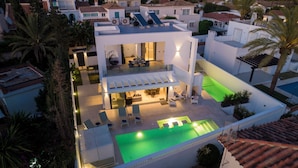 Ein modernes Haus mit Pool auf dem Dach, Sitzgelegenheiten im Freien und einem hellen Innenraum.