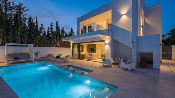 Ein modernes, zweigeschossiges Haus mit Pool, Außenbereich und gut beleuchtetem Innenraum.