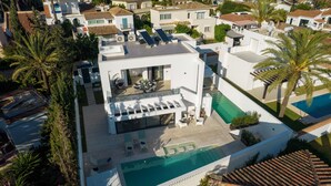 Eine Vogelperspektive auf ein modernes Wohnanwesen mit Swimmingpool, Liegestühlen und einer überdachten Sitzterrasse.