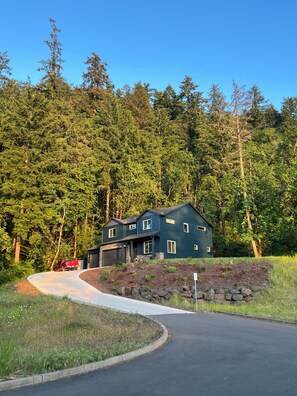 A two-story house with a dark blue exterior, a driveway, and a red truck parked nearby. - Forest home and outdoor adventure paradise! (Springfield)