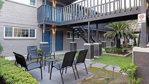 A modern building with a grey brick exterior, a blue door, and a balcony with a metal railing. - 2BR The TMC Flats 04! Hermann Park Zoo! (Houston)