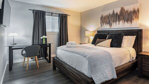 A modern hotel room with a bed, desk, chair, and artwork on the wall. - 2BR The TMC Flats 04! Hermann Park Zoo! (Houston)