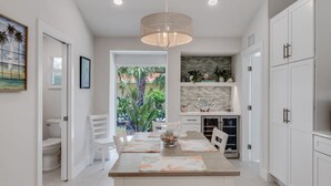 Una cocina moderna con gabinetes blancos, una mesa de comedor con individuales y una lámpara colgante.