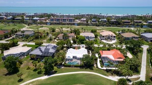 Vista aérea de un complejo turístico con varias edificaciones, un campo de golf y una playa.