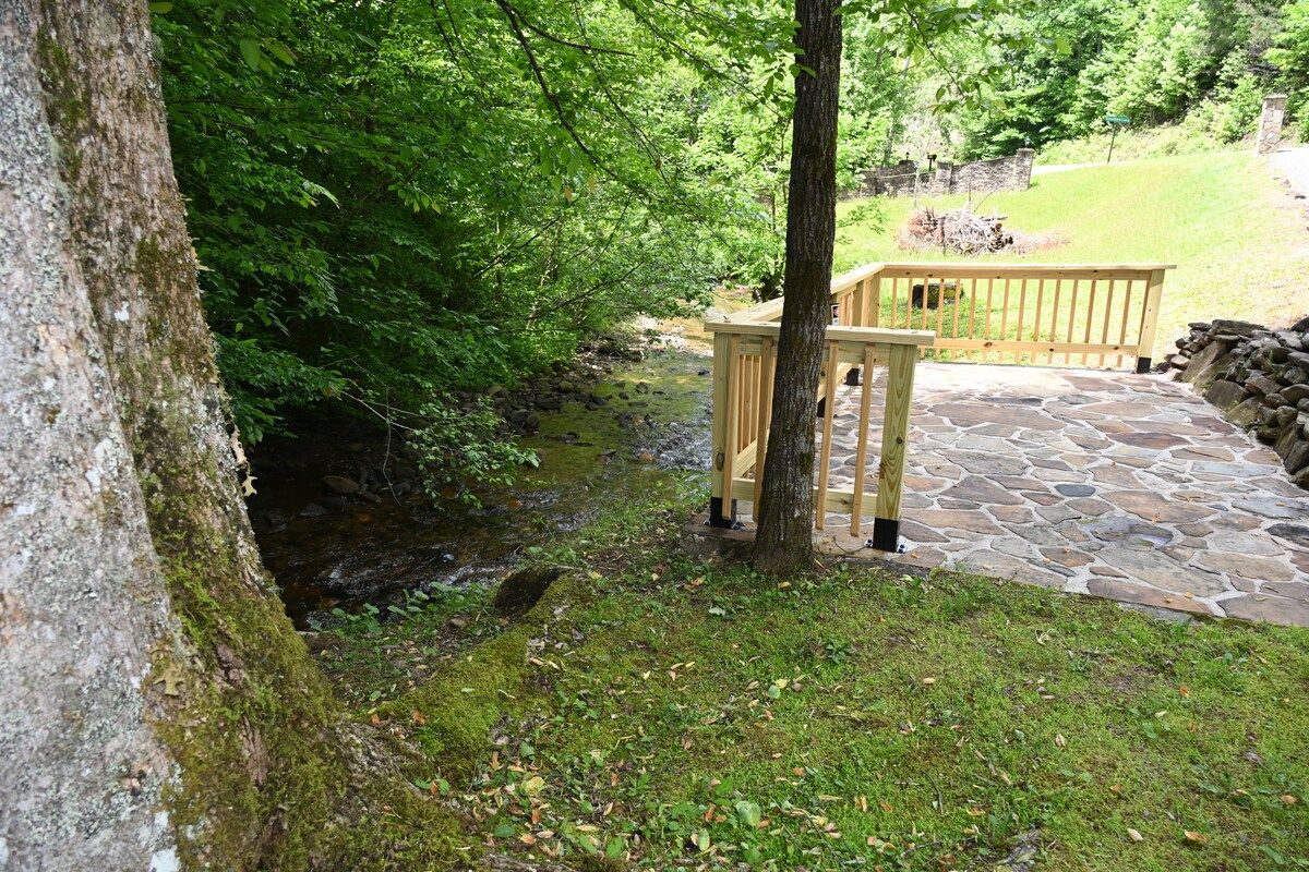 A stone pathway leading to a wooden deck with a stone wall in the background.