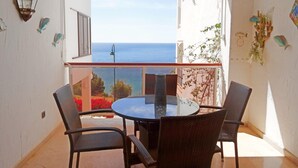 Uma varanda com mesa e cadeiras, com vista para o mar.