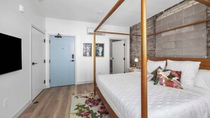 Ein modernes Schlafzimmer mit Himmelbett, blauer Tür und Backsteinwand.