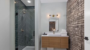 Ein modernes Badezimmer mit Glasdusche, Holzwaschtisch und einer Wand aus Ziegelsteinen.