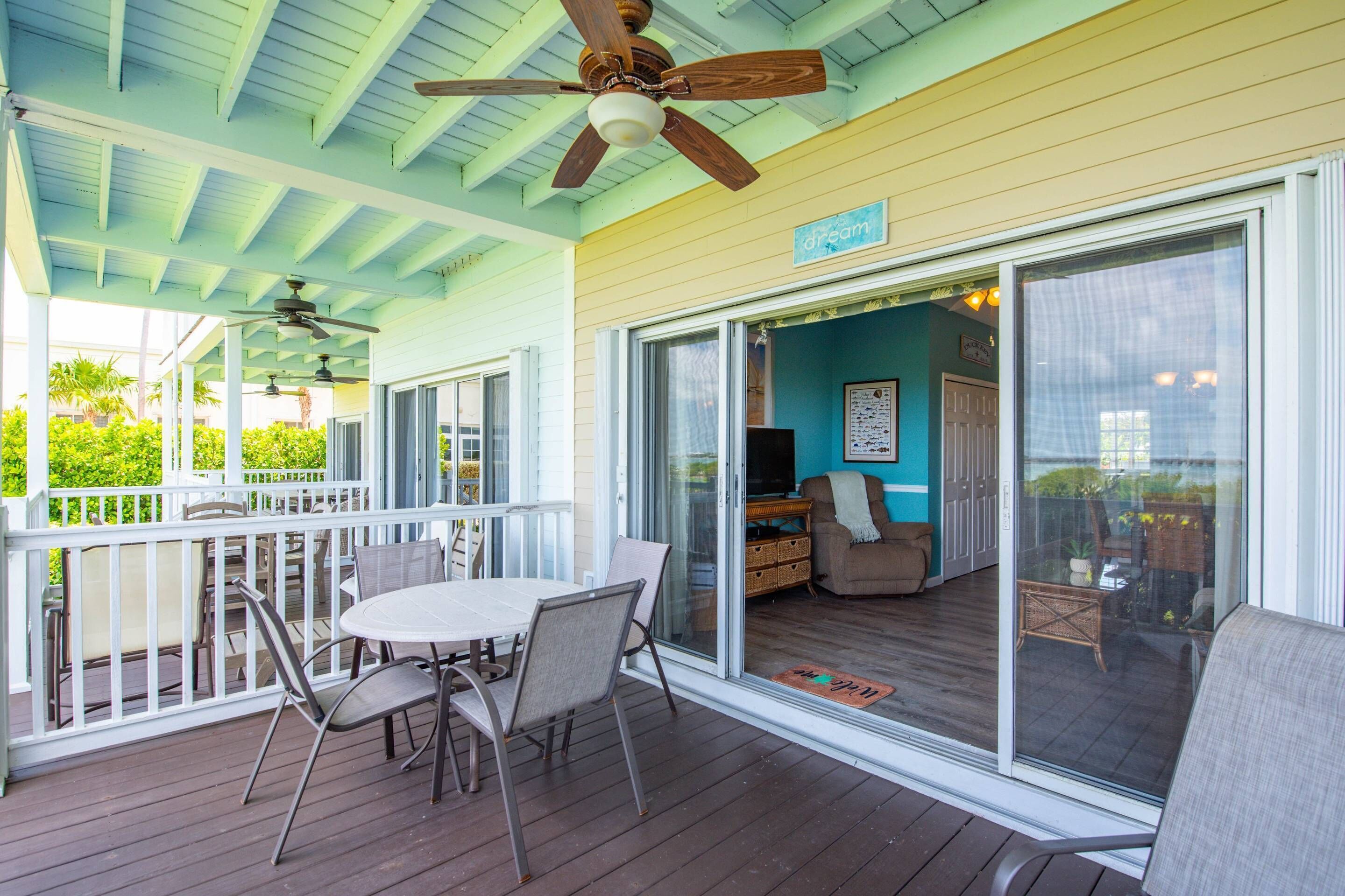 A covered outdoor patio with a table and chairs, a ceiling fan, and a sliding glass door leading to an interior living area.