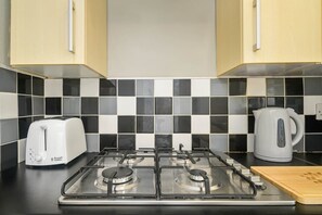 A kitchen with a gas stove, a toaster, and a kettle.
