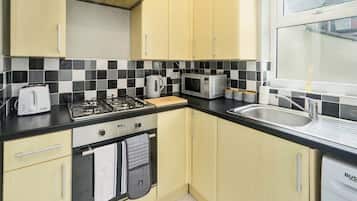 A kitchen with a gas stove, microwave, toaster, and sink.