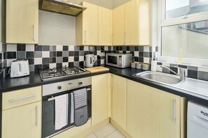 A kitchen with a gas stove, microwave, toaster, and sink.