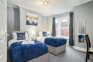 A hotel room with two beds, a large window, a painting on the wall, and a mirror. - Willow House - 2-Bedroom House In Merseyside (Merseyside)