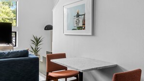 Uma sala de estar moderna com um sofá, uma mesa de jantar e um quadro na parede.