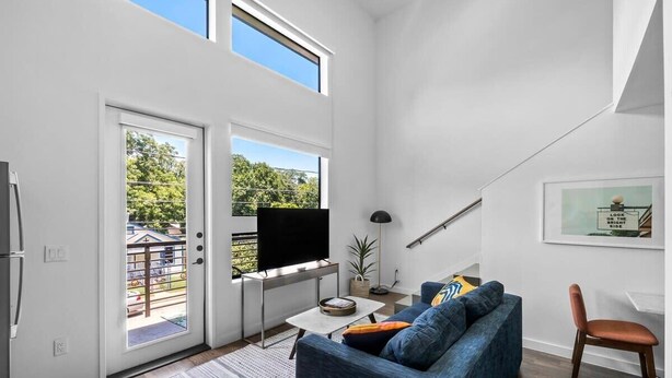 Uma sala de estar moderna com sofá, mesa de centro, TV de tela plana e escada.