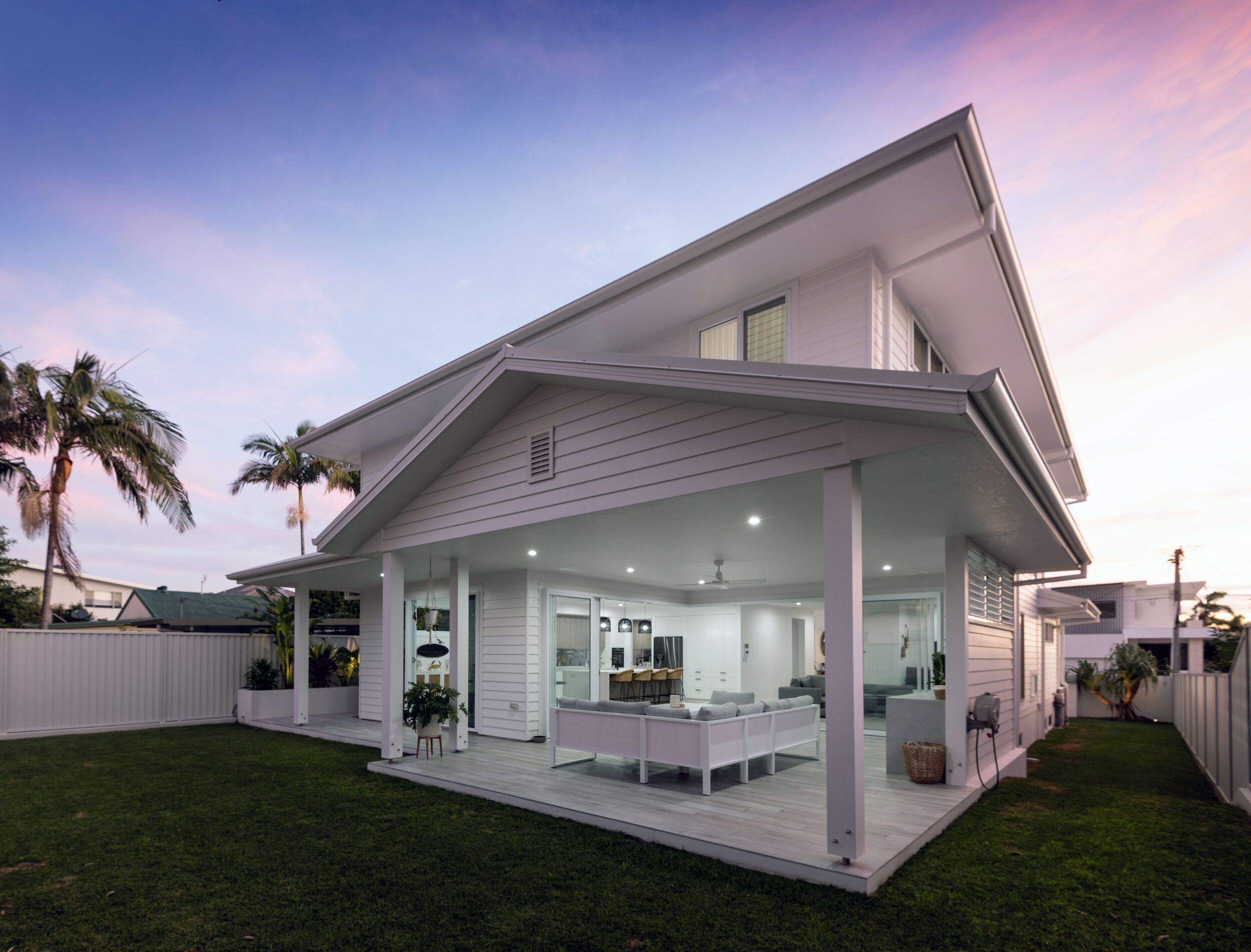 A modern two-story house with a covered patio, a kitchen with a dining area, and a small outdoor seating space.